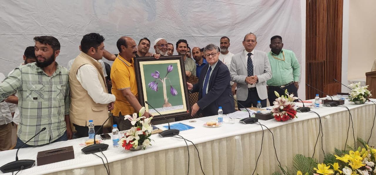 Saffron growers presenting framed saffron-flower art to a senior official at a delegation meeting