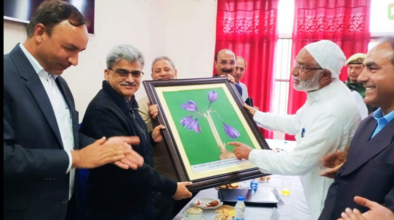 Our family elder handing a framed display of Kashmiri saffron flowers to senior officials