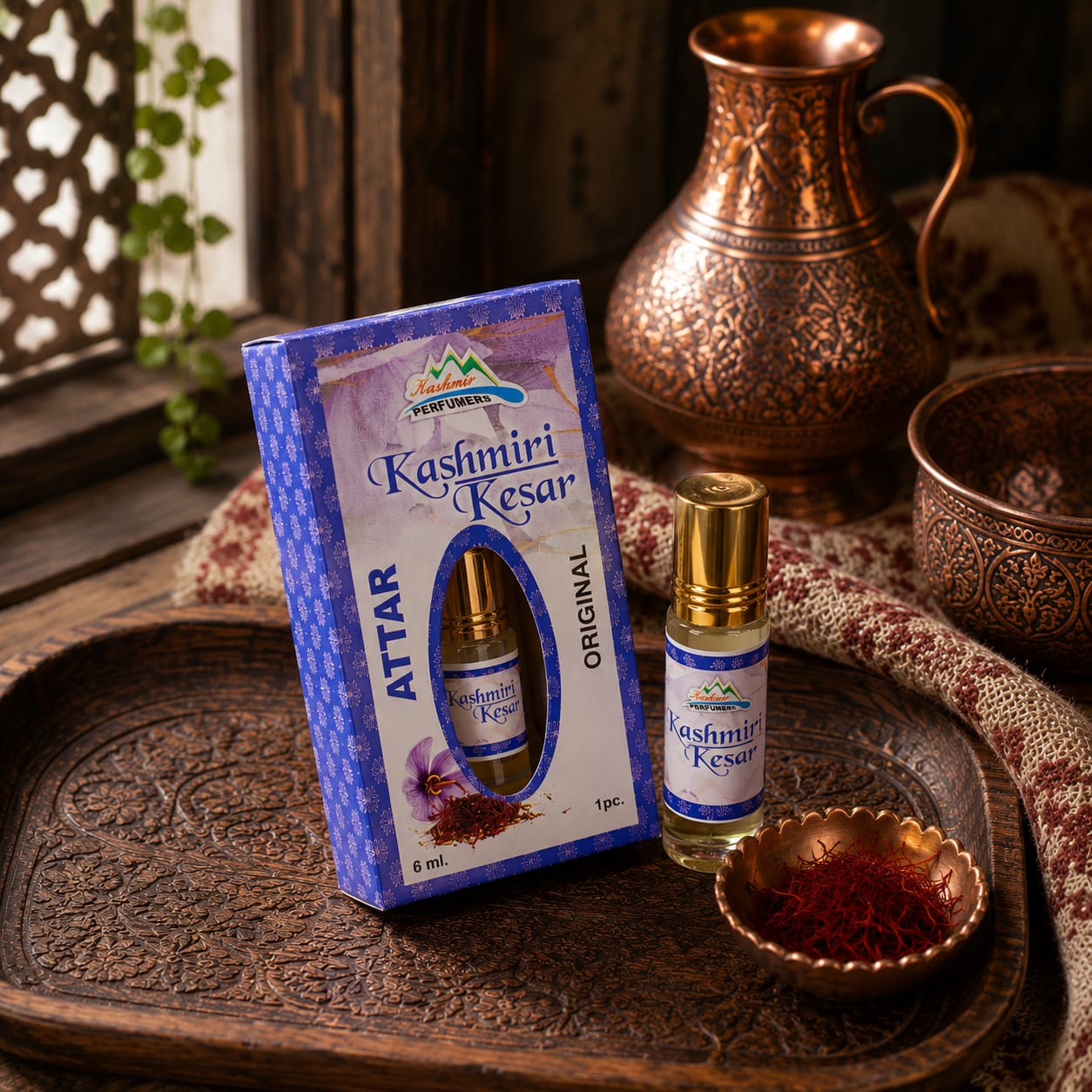 A boxed 6 ml Kashmiri Kesar attar and its roll-on bottle on a carved tray, beside a copper dish of saffron threads