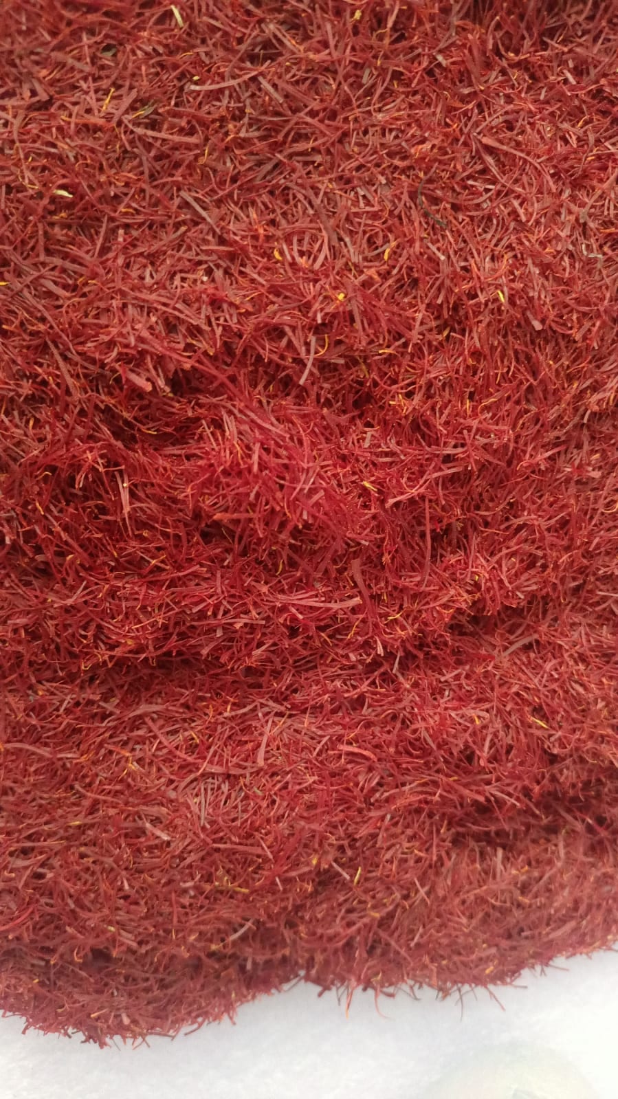 A dense mass of dried red threads filling the frame, with a scattering of yellow style fragments among them