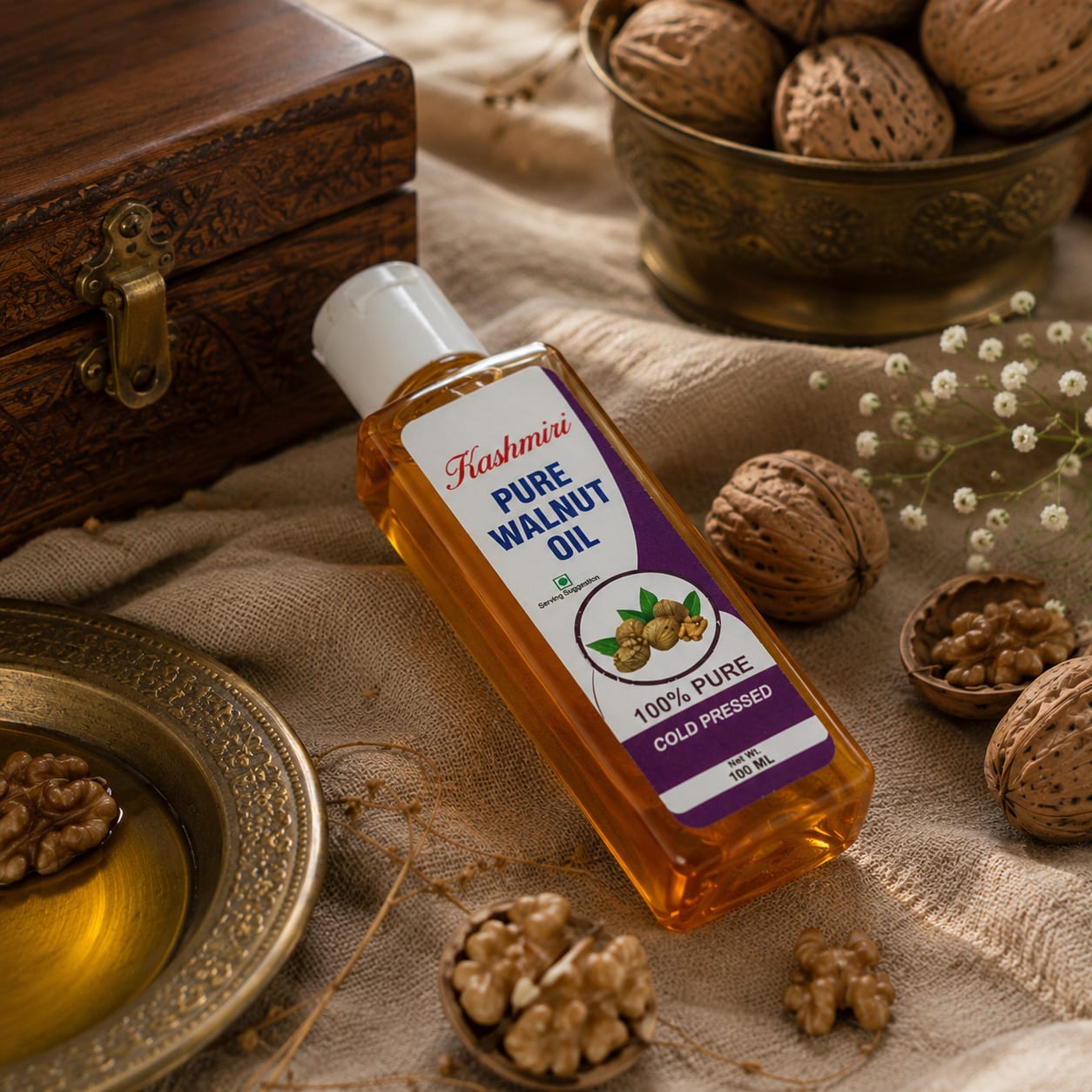 The walnut oil bottle lying on linen among shell-on walnuts and loose kernels, a brass dish of oil to the left